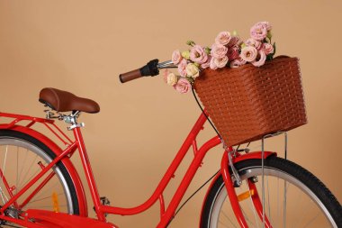 Soluk turuncu arka planda güzel çiçekli bisiklet sepeti, yakın plan.