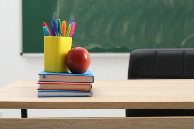 Farklı okul kırtasiyesi ve ahşap masa üzerinde kırmızı elma, kapalı alanda yazı için yer var.