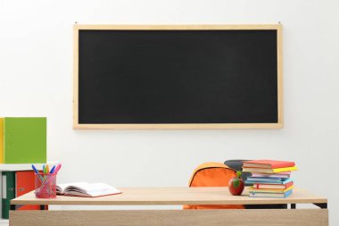 Farklı kırtasiye malzemesi ve kırmızı elma, kapalı alanda, tahtanın yanında.