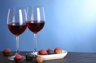 Lezzetli yer mantarı bonbonları ve mavi arka planda siyah masada şarap. Metin için boşluk