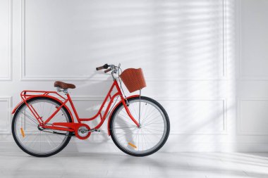 Beyaz duvarın yanında sepeti olan kırmızı bisiklet. Metin için boşluk