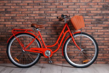 İçeride tuğla duvarın yanında sepeti olan kırmızı bisiklet.