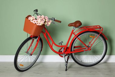 Açık yeşil duvarın yanında bir sepet güzel çiçekli bisiklet.