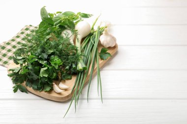 Farklı taze otlar, yeşil soğanlar ve beyaz ahşap masada sarımsak. Metin için boşluk