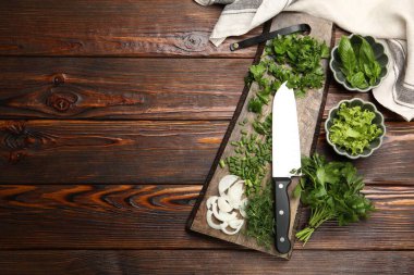 Farklı taze otlar, baharatlar ve tahta masa üzerinde bıçak, düz yatak. Metin için boşluk