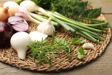 Farklı taze otlar, soğanlar ve sarımsak ahşap masada, yakın plan.