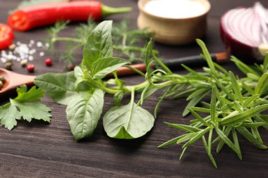 Farklı taze otlar ve baharatlar ahşap masada, yakın plan.