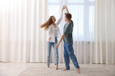 Mutlu genç çift evde dans ediyor.