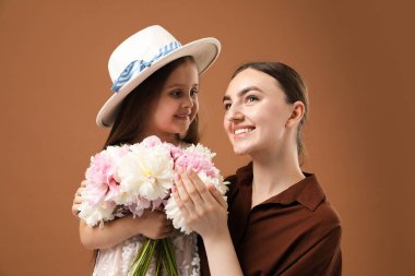 Anne ve kızı kahverengi arka planda bir buket güzel şakayıkla