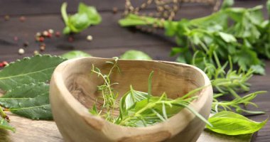 Havana biber ekleyen kadın ahşap masada farklı taze otlar, yakın plan.