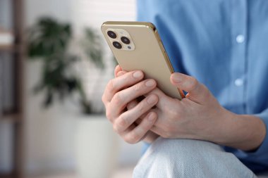 Evde modern akıllı telefon kullanan bir kadın, yakın çekim. Metin için boşluk