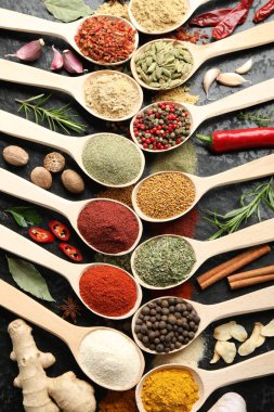 Gri masadaki kaşıklardaki farklı baharatlar düzdü.