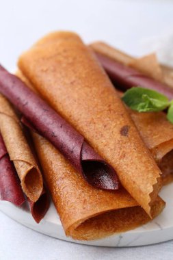 Lezzetli meyve ruloları ve nane şekeri ışık masasında, yakın plan.