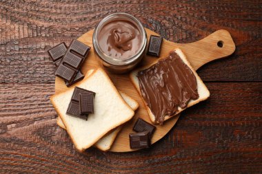 Lezzetli çikolatalı tereyağı, parçalar ve ekmek ahşap masada, üst manzara