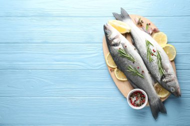 Mavi ahşap masadaki baharatlı taze çiğ deniz kabuğu balığı, üst manzara ve yazı için yer. Deniz ürünleri lezzetleri.