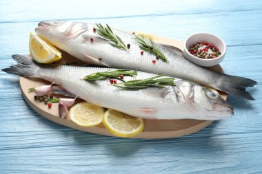 Mavi ahşap masada baharatlı taze çiğ deniz kabuğu, yakın plan. Balık ve deniz ürünleri lezzetleri