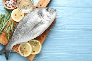 Mavi ahşap masa üzerinde baharatlı taze çiğ dourade balığı, düz ve metin için alan. Deniz ürünleri lezzetleri.