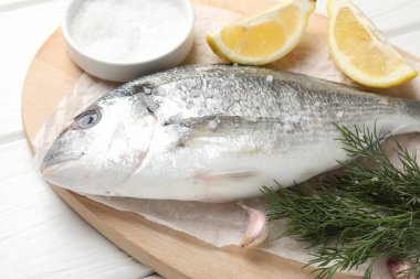 Beyaz ahşap masadaki baharatlı taze çiğ dourade, yakın plan. Balık ve deniz ürünleri lezzetleri