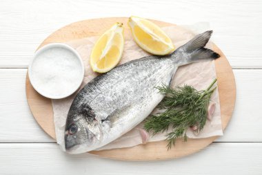 Beyaz ahşap masa üzerinde baharatlı taze çiğ dourade, üst manzara. Balık ve deniz ürünleri lezzetleri