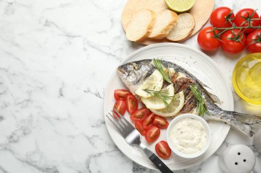 Lezzetli kızarmış dorado balığı, ekmek, sos, domates ve limonlu beyaz mermer masa, düz yatak ve yazı için yer. Ev yapımı deniz ürünleri yemeği.