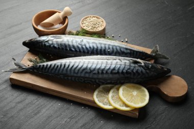 Siyah masada taze çiğ uskumrular ve baharatlar, yakın plan. Deniz ürünleri lezzetleri.