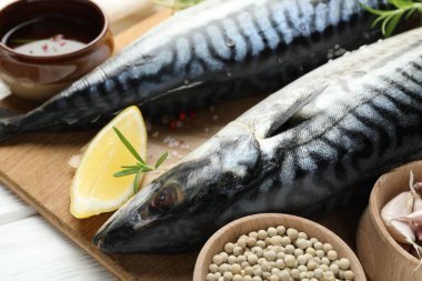 Beyaz ahşap masada taze çiğ uskumrular ve baharatlar, yakın plan. Deniz ürünleri lezzetleri.