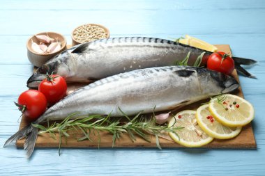 Açık mavi ahşap masada taze çiğ uskumrular ve baharatlar, yakın plan. Deniz ürünleri lezzetleri.