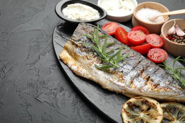 Ev yapımı deniz ürünleri yemeği. Siyah masanın üstünde baharat ve sosla servis edilen lezzetli kızarmış uskumrular. Metin için boşluk