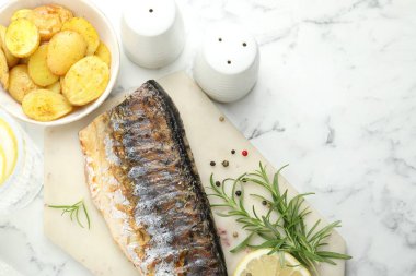 Ev yapımı deniz ürünleri yemeği. Beyaz mermer masada baharatlı ve patatesli kızarmış uskumru. Metin için boşluk