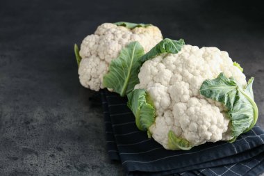 Gri masadaki yeşil yapraklı taze karnabahar kafalar, yakın plan. Metin için boşluk