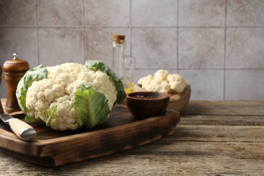 Yeşil yapraklı taze karnabahar, ahşap masada baharatlar ve bıçak, yakın plan. Metin için boşluk