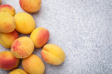 Gri desenli masa üzerinde bir sürü taze kayısı, düzlük. Metin için boşluk