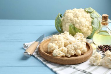 Karnabahar, biber, yağ ve bıçak parçaları açık mavi ahşap masada. Metin için boşluk