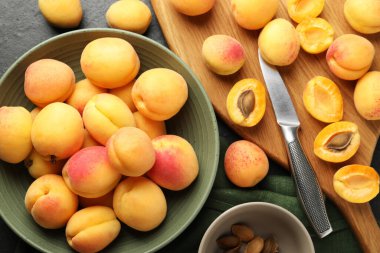 Taze kayısılar kasede, çekirdekler ve bıçak siyah masada, düz yatıyordu.