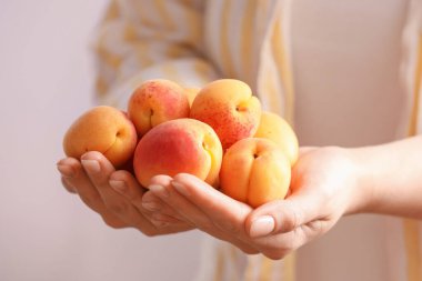 Hafif arka planda taze olgun kayısıları olan kadın, yakın plan.