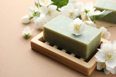 Açık kahverengi arka planda sabun ve yasemin çiçekleri, yakın plan.