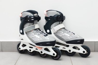 Beyaz duvarın yanında yerde bir çift paten var.