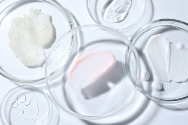 Petri kaplarında farklı kozmetik ürünleri beyaz arka planda, yakın planda