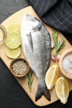 Siyah masadaki baharatlı taze çiğ dourade, üst manzara. Balık ve deniz ürünleri lezzetleri