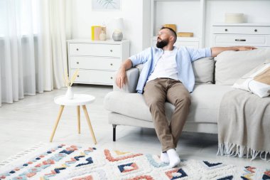 Uyum. Evdeki rahat koltukta dinlenen bir adam.