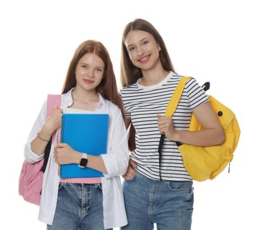 Sırt çantalı ve beyaz arka planda defterleri olan genç kızlar.