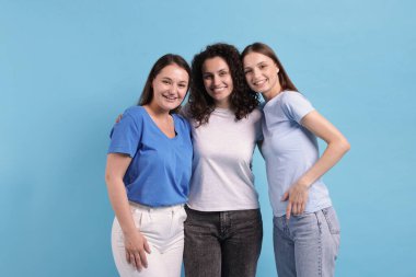 Açık mavi arka planda sarılan üç arkadaş