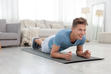 Evde tahta egzersizi yapan bir adam. Spor ve sağlıklı yaşam tarzı