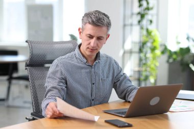 Ofisteki masada belgelerle çalışan bir işadamı.