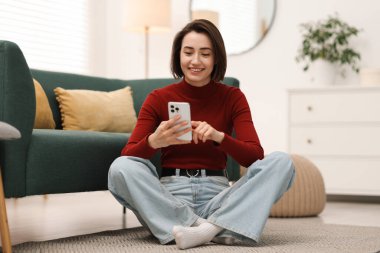 Evde modern akıllı telefon kullanan bir kadın.