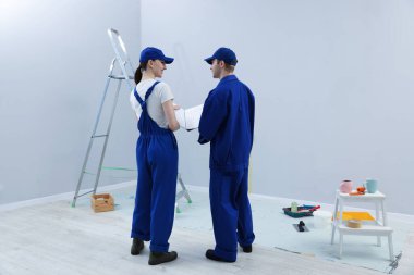 Tasarım projesine bakan işçiler odada, arka planda