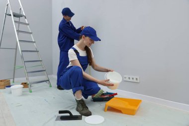 Farklı ekipmanlara sahip işçiler odada tadilat yapıyorlar. Metin için boşluk