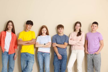 Bej duvarın yanında bir grup genç.