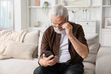 Evdeki kanepede akıllı telefon kullanan görme sorunu olan son sınıf öğrencisi.