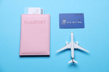 Uçak modeli, uçuş bileti, pasaport ve kredi kartı açık mavi arka planda, düz konum